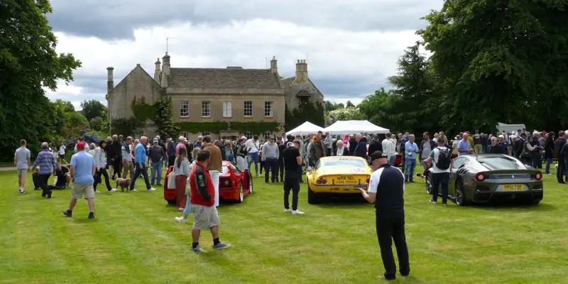 A photo of a house and cars, with people walking around