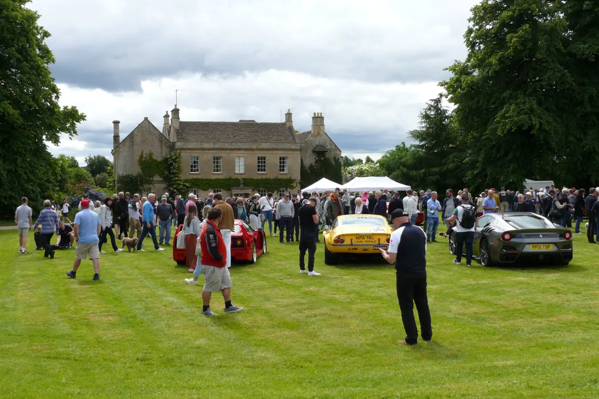 A photo of a house and cars, with people walking around
