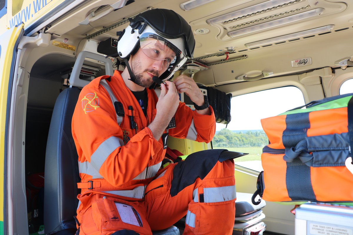 A photo of doctor Jono Holme securing his helmet, whilst sat in the helicopter