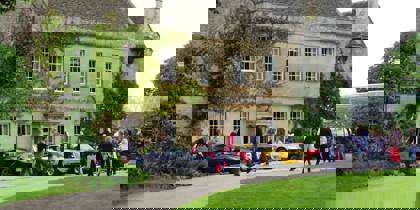 A photo of Middlewick House with sports cars parked outside and visitors taking photos and looking at the cars.