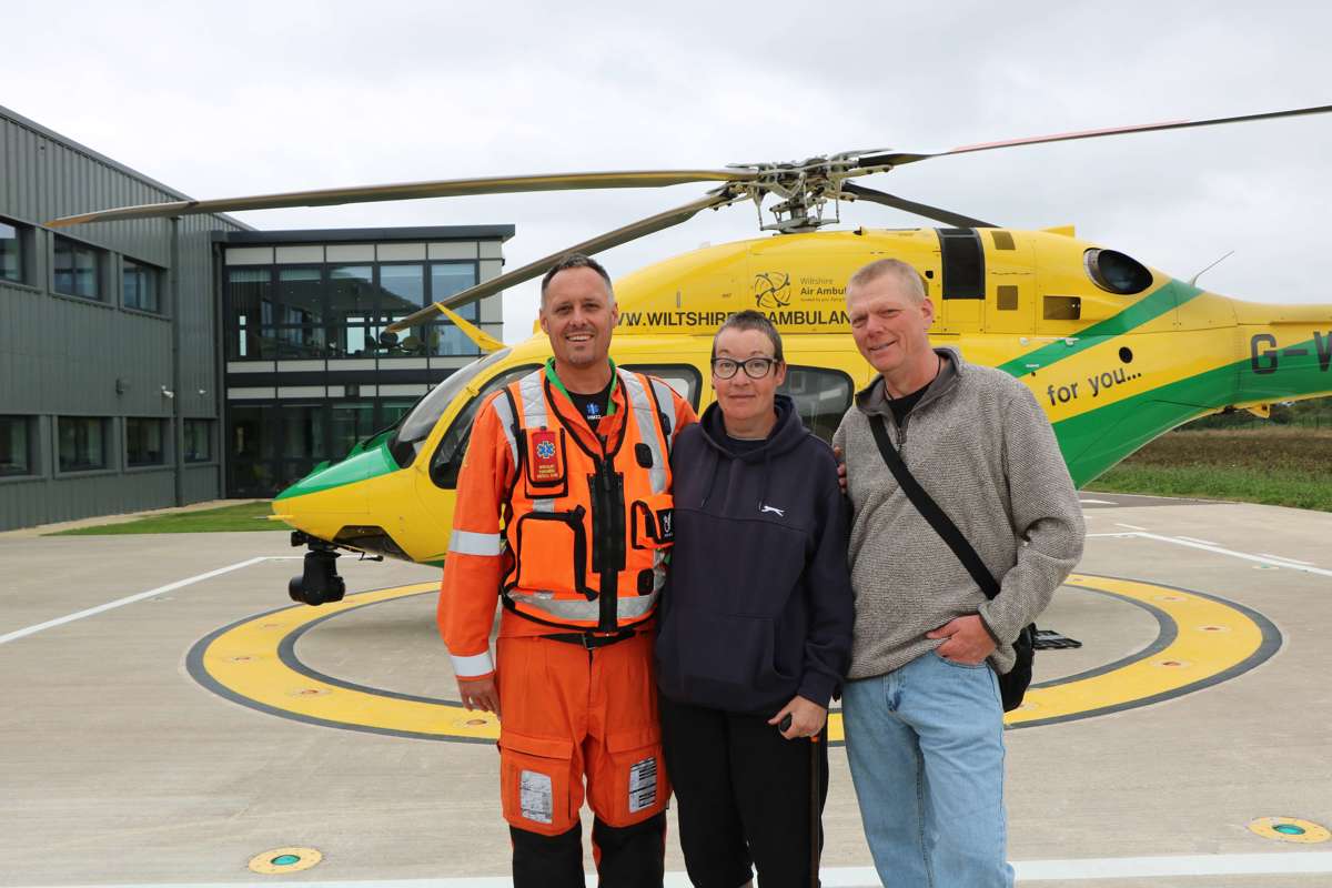 A former patient and their partner stood with a critical care paramedic in front of the Bell-429 helicopter. A former patient and their partner stood with a critical care paramedic in front of the Bell-429 helicopter.