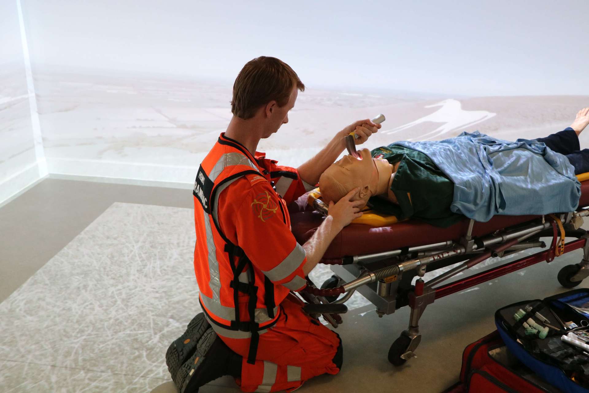 A critical care paramedic doing training in a simulation room using medical equipment and a mannequin. A critical care paramedic doing training in a simulation room using medical equipment and a mannequin.