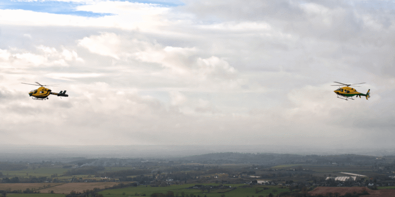 The old Wiltshire Air Ambulance MD-902 helicopter in the air, flying alongside the new Bell-429 helicopter.