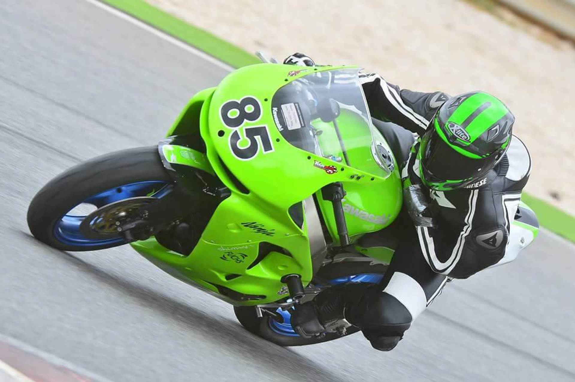 A motorcyclist on a green motorbike