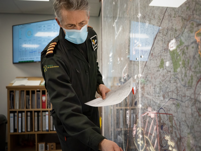 Pilot Elvis wearing a face mask and planning a route on a map in the Wiltshire Air Ambulance ops room