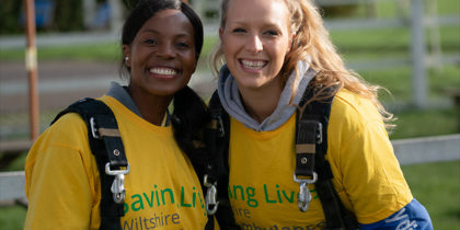 Two people wearing yellow t-shirts and GoSkydive overalls at a skydive event Two people wearing yellow t-shirts and GoSkydive overalls at a skydive event