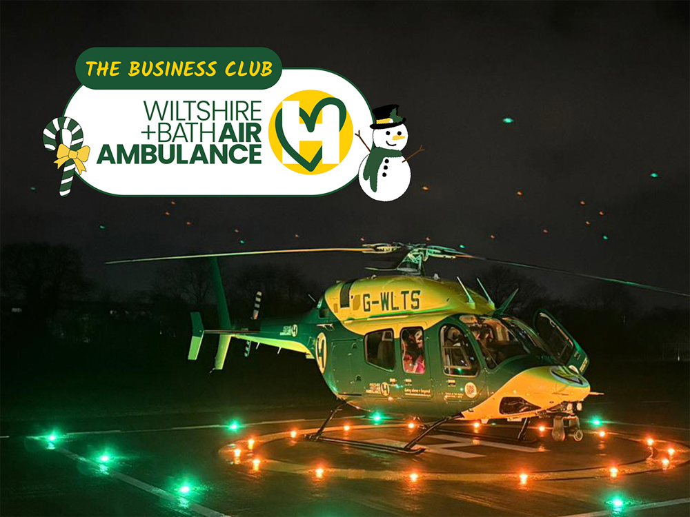 The Bell-429 helicopter at night, sat on a lit helipad with yellow and green lights on.