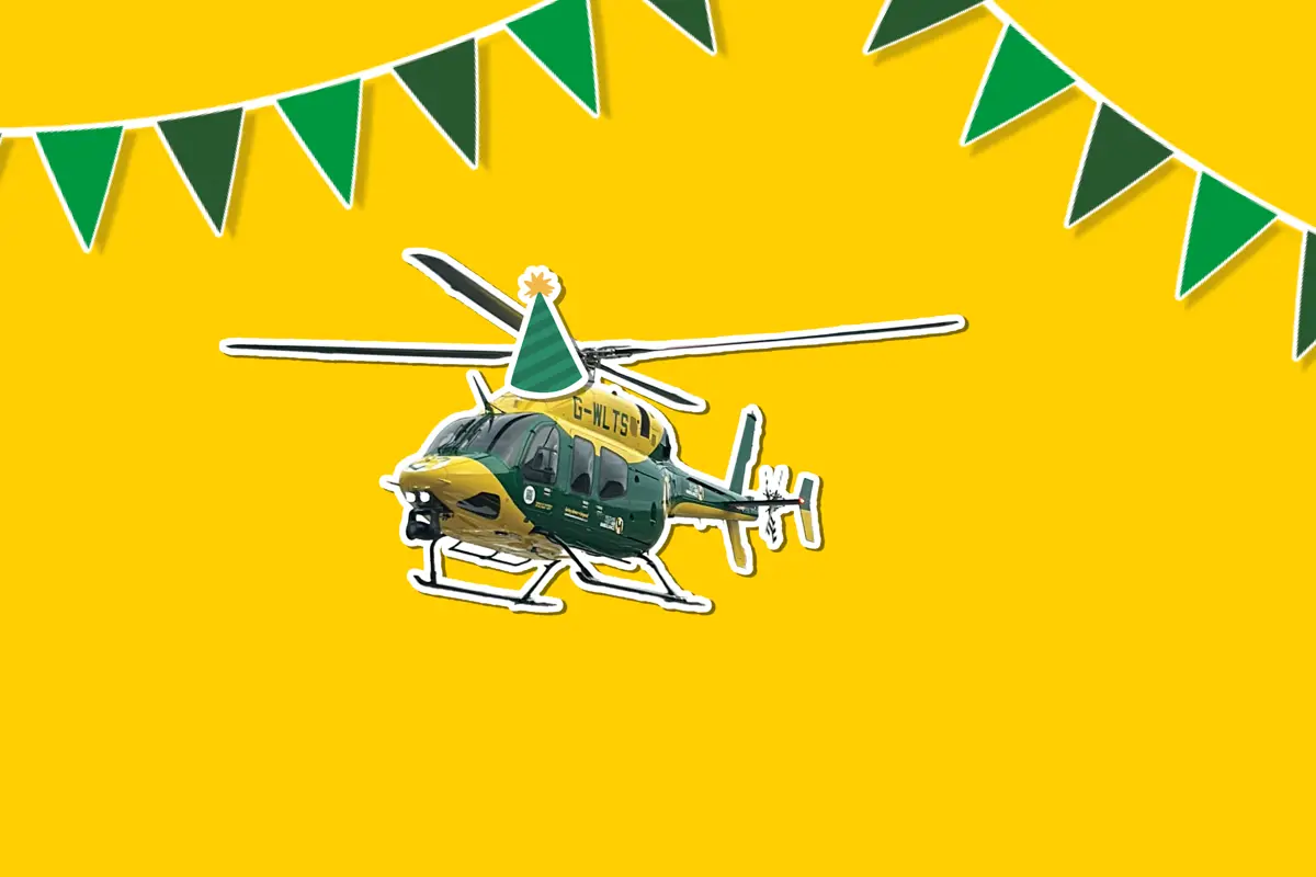 A yellow background with a sticker of the yellow and grey Bell 429 helicopter wearing a cartoon sticker hat, with green bunting around it A yellow background with a sticker of the yellow and grey Bell 429 helicopter wearing a cartoon sticker hat, with green bunting around it