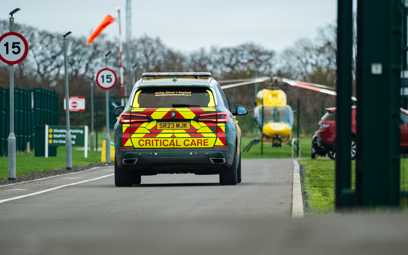 Wiltshire and Bath Air Ambulance's critical care car driving down the drive with the helicopter in view Wiltshire and Bath Air Ambulance's critical care car driving down the drive with the helicopter in view