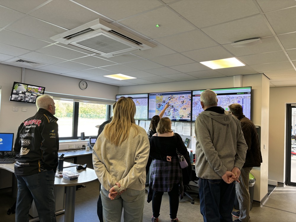 A group of people being shown screens in a flight room A group of people being shown screens in a flight room