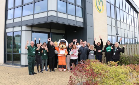 The charity team and mascot celebrating outside the airbase holding a vase award and certificate