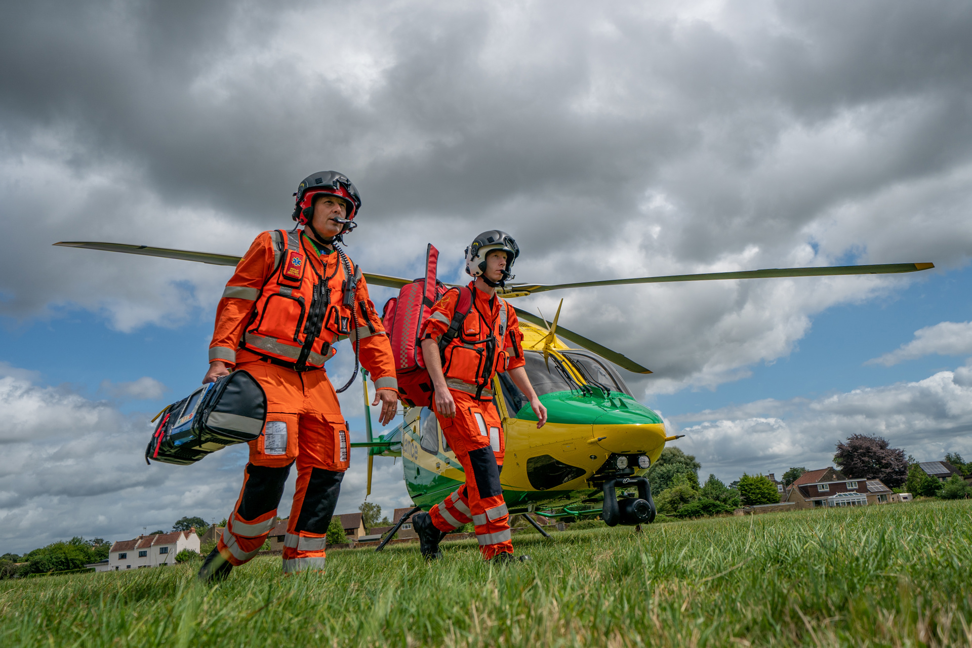 Two paramedics walking away from the helicopter towards a staged incident in a field