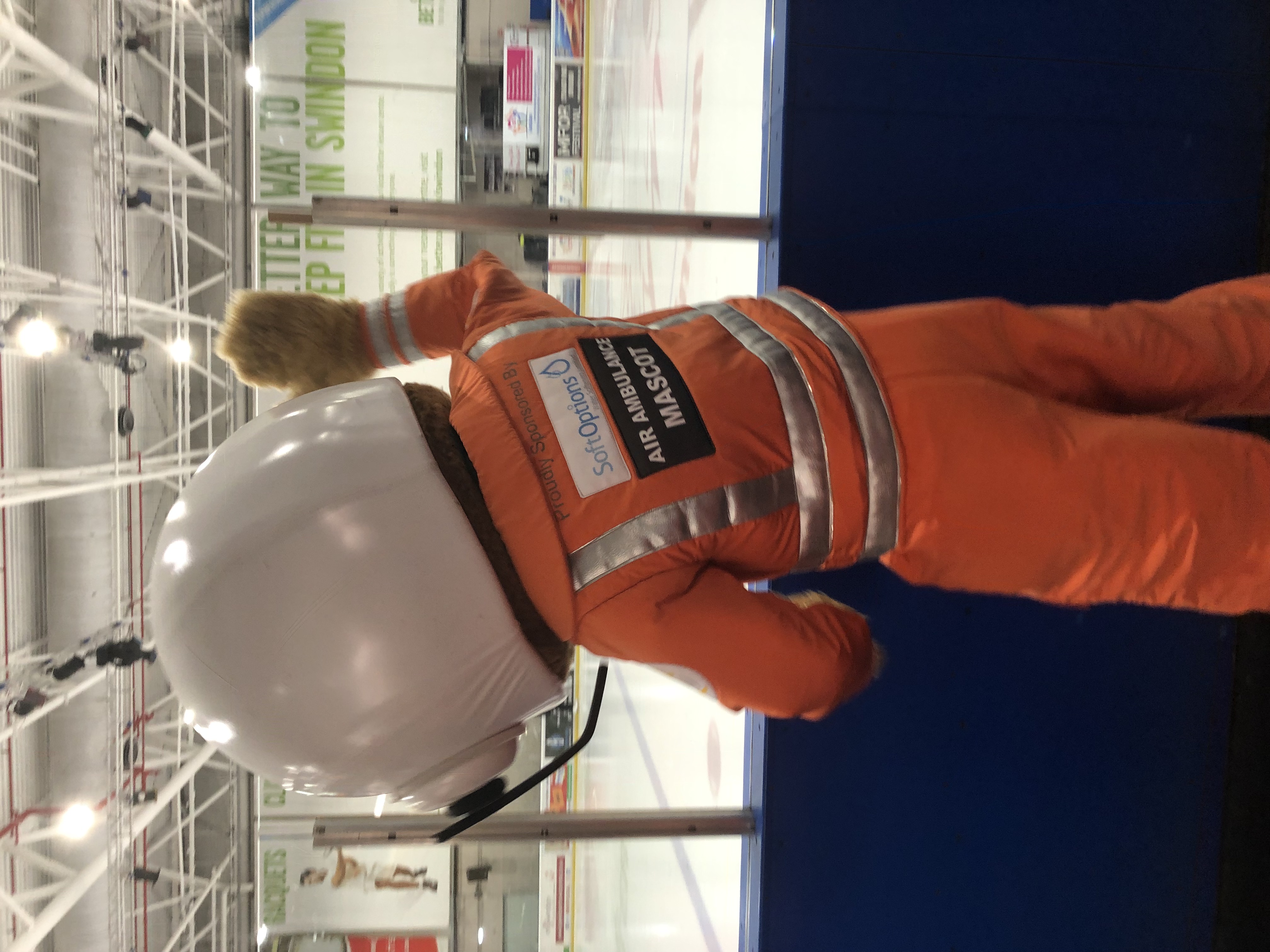 An air ambulance paramedic mascot cheering at the side of an ice rink