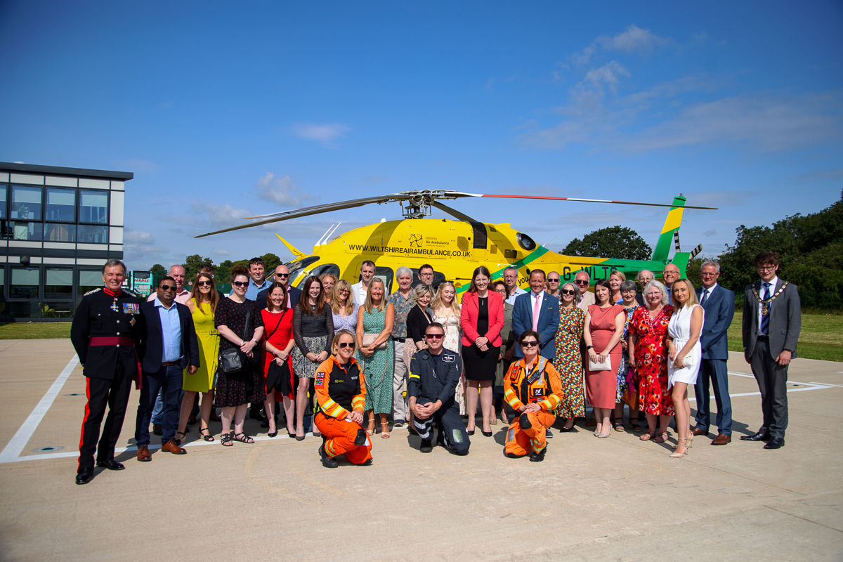 A photo of the Coombe Castle team by the wiltshire air ambulance aircraft on a sunny day