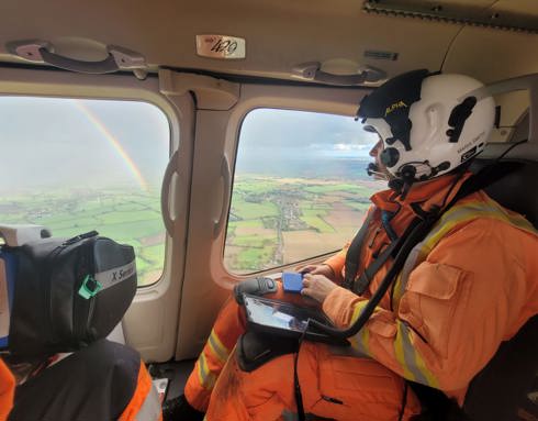 A critical care doctor in an air ambulance, looking out the window to see a rainbow