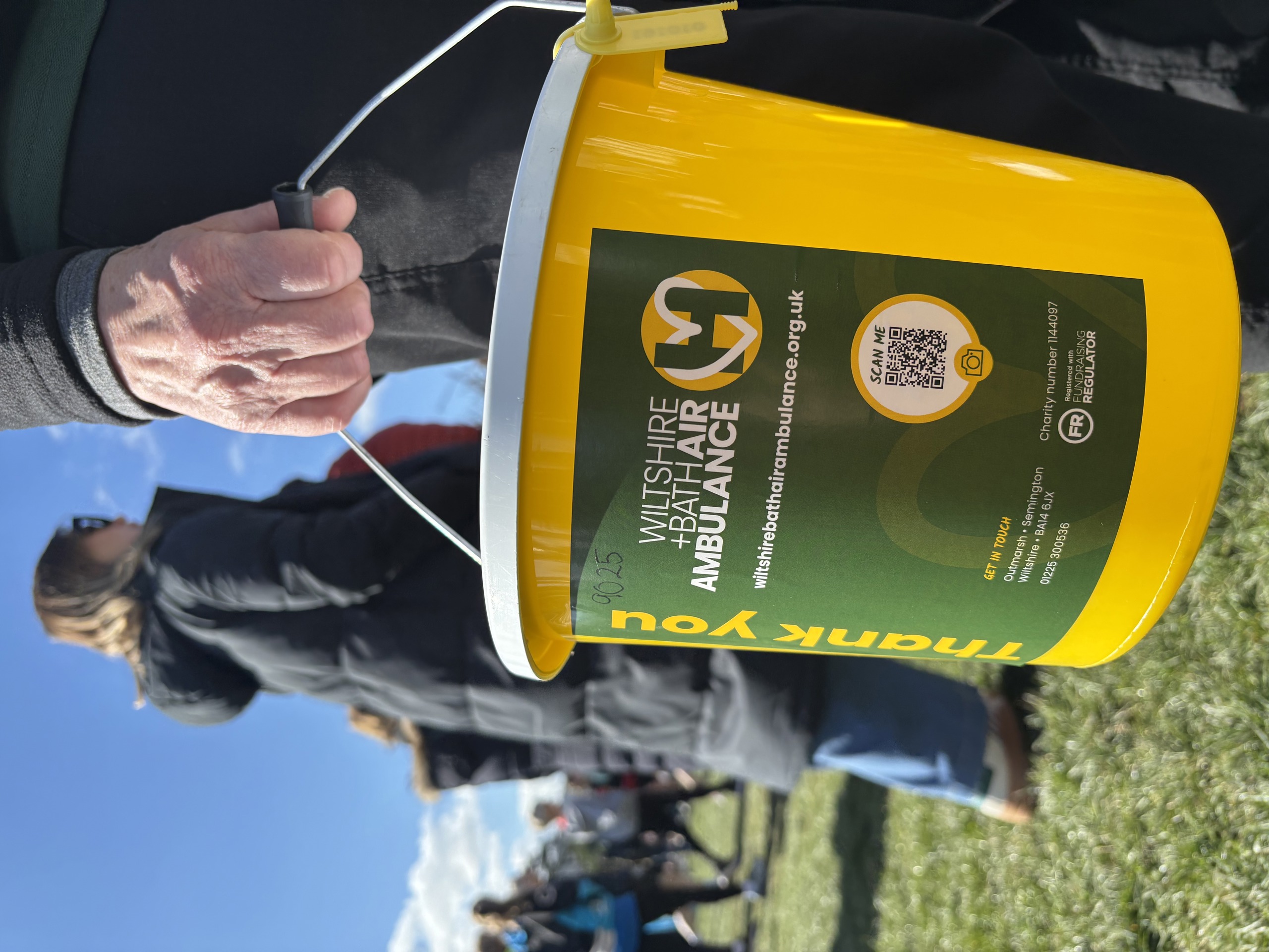A yellow collection bucket with green label showing W+BAA logo and donation information A yellow collection bucket with green label showing W+BAA logo and donation information