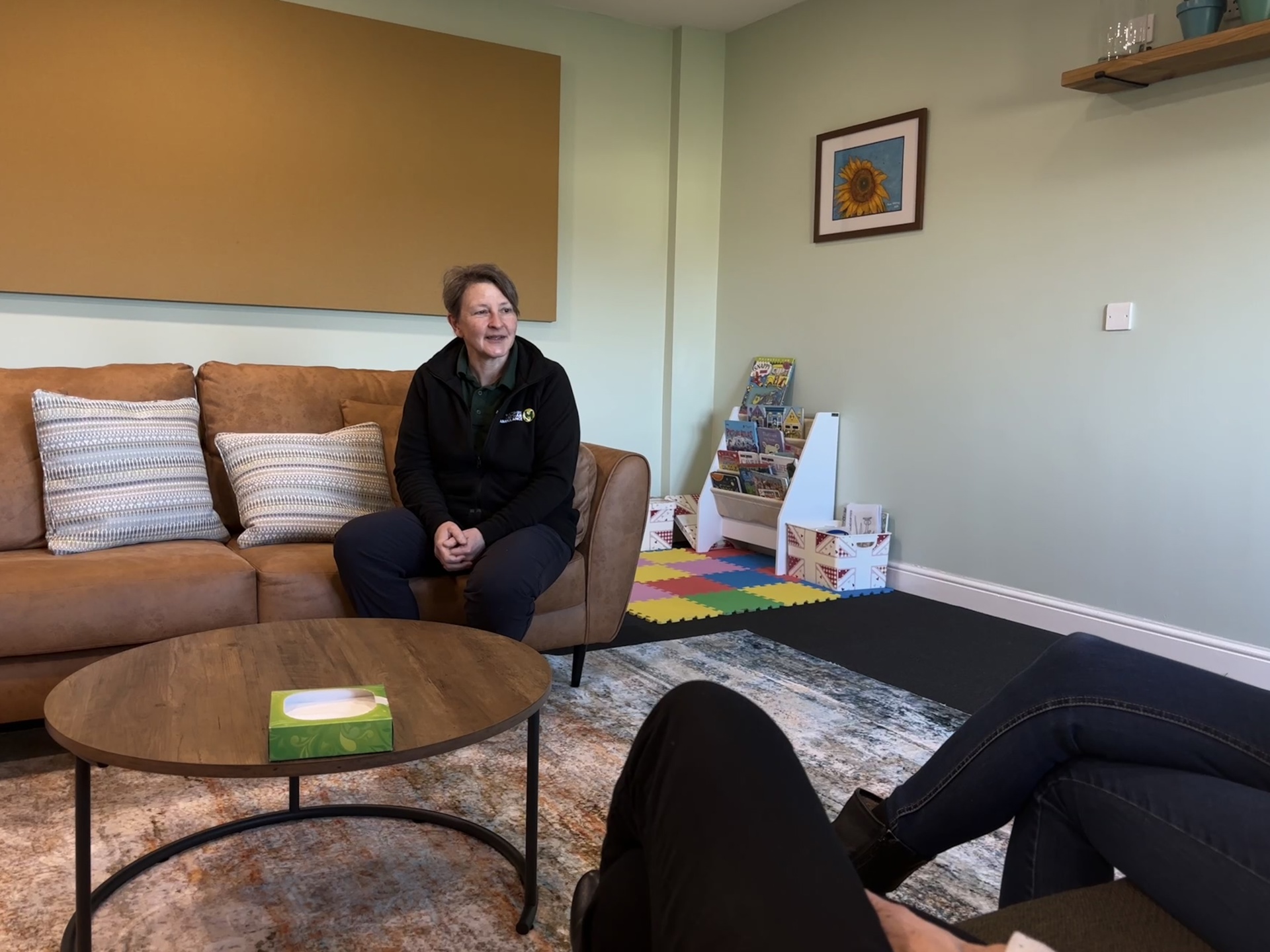 A photo of a lady sitting on a sofa speaking to two people