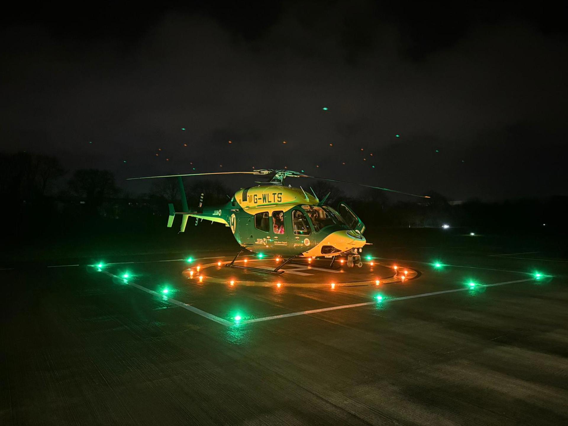 Wiltshire and Bath Air Ambulance Charity's new look helicopter on their helipad at night with the lights on